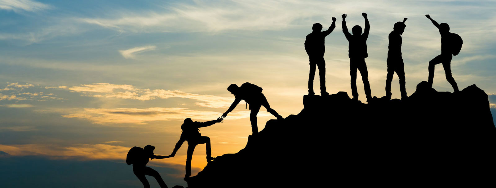 people reaching a summit by helping each other