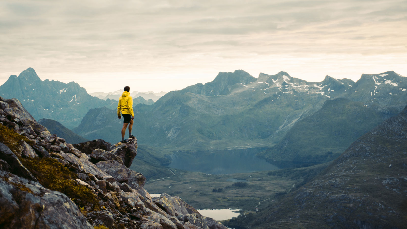 man standing on a overhang looking at some mountains on a grey day - investing for growth